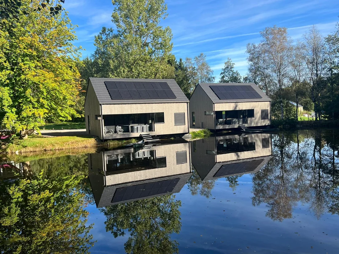 Chalets en pin thermo-traité pré-grisé, posés au bord de l'eau.