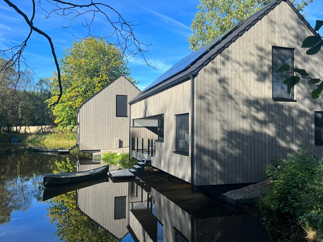Chalets bardés en pin thermo-traité pré-grisé, pose verticale, au bord de l'eau